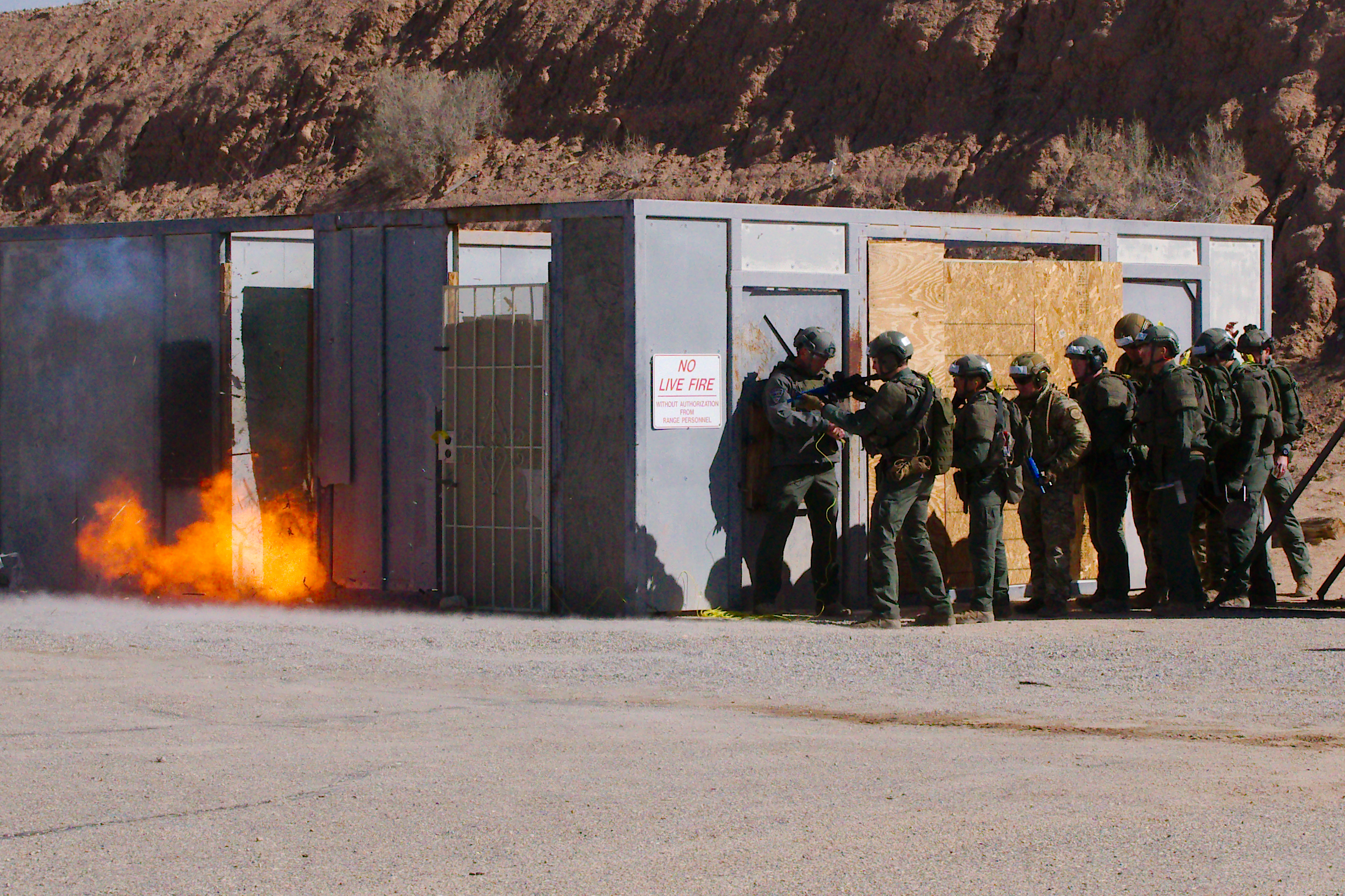 A tactical team takes cover as an explosive breach is conducted during a training exercise