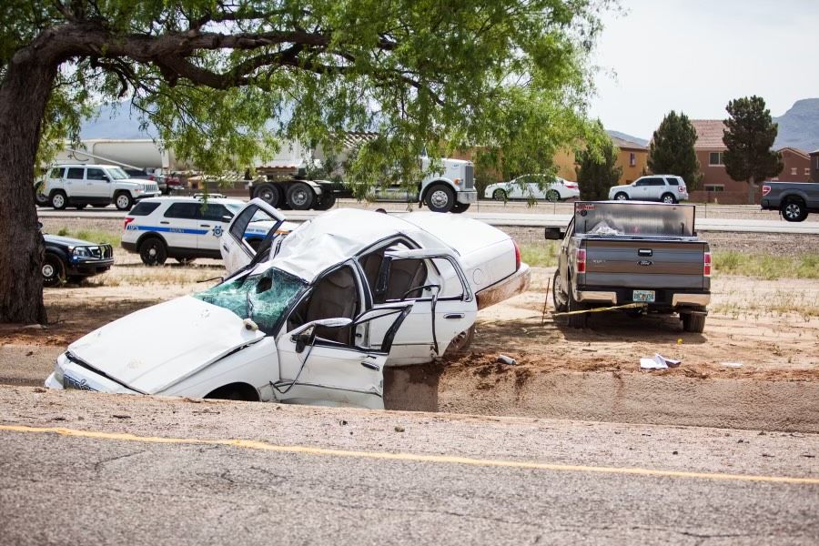 a white sedan that is wrecked and stuck in a drain culvert